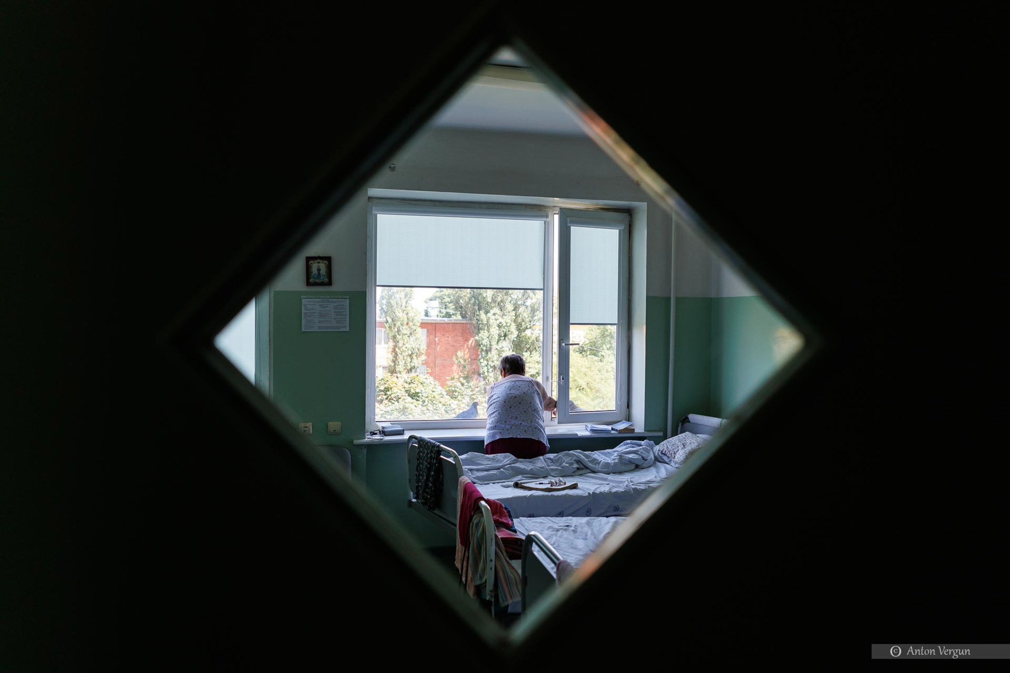 Пациент кормит голубей через открытое окно в палате кардиологического отделения №1 в областной клинической больнице Святителя Иоасафа.  22 июля 2023 года